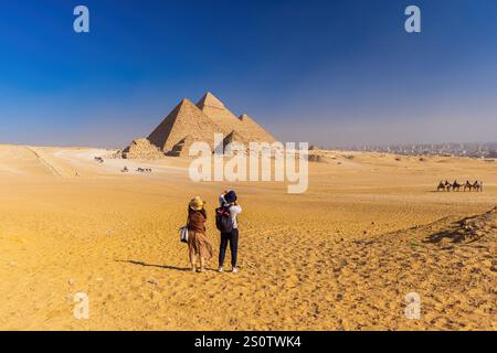 GIZEH, ÄGYPTEN - 23. DEZEMBER 2024: Ein Touristenpaar macht Fotos von den Pyramiden von Gizeh. Stockfoto
