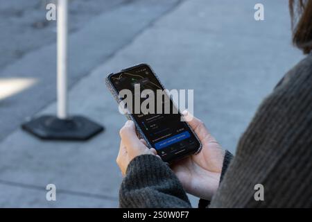 Eine Frau nutzt die Waymo One App, um am Donnerstag, den 27. November 2024, eine Fahrt mit dem Robotaxi vom Portsmouth Square in Chinatown zum Pier 33 in San Francisco zu feiern. Stockfoto