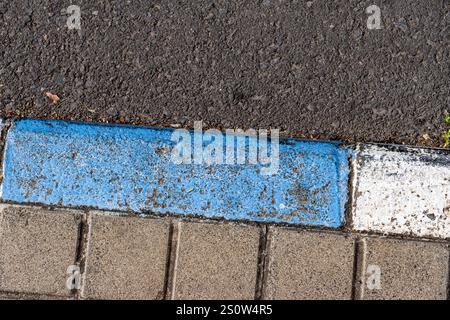 Auf einem grauen Gehweg ist eine blaue Linie gemalt, die einen Kontrast zwischen den beiden Farben schafft. Die blaue Linie befindet sich neben einem grauen Bürgersteig, der ein Stockfoto