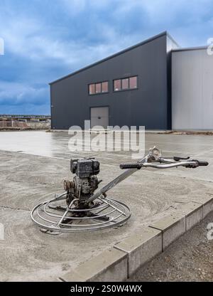 Betonveredelung mit einer Kehlmaschine auf einer frisch gegossenen Betonplatte auf einer Industriebau Stockfoto