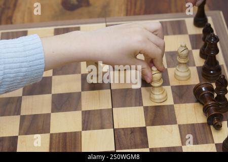 Nahaufnahme der Hände eines Kindes, die Schach spielen, mit weißem Hintergrund und Kopierraum Stockfoto