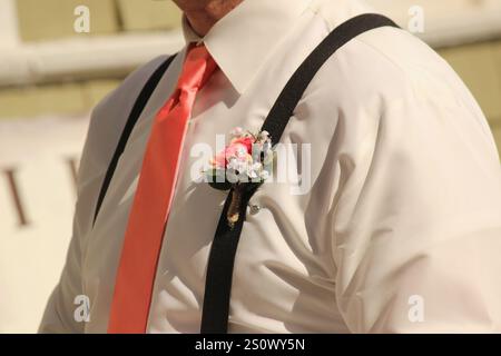 Der Trauzeuge trägt eine Boutonnière an seinen Hosenträgern während einer Hochzeit Stockfoto