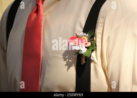 Der Trauzeuge trägt eine Boutonnière an seinen Hosenträgern während einer Hochzeit Stockfoto