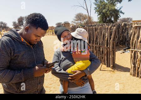 afrikanisches Dorf , Sozialarbeiter Freiwillige, die Telefon-Unterricht drahtlose Technologien für Dorfbewohner, Mutter und Tochter mit Zöpfen, Outdoor Küche, Stockfoto