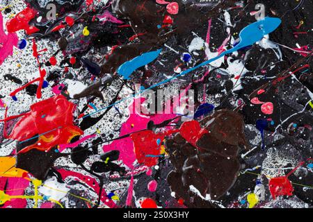 Nahaufnahme einer abstrakten, unordentlichen und bunten Acrylfarbe auf schwarzem Hintergrund. Spritzer, Klumpen, Tropfen, Flecken und Sprühnebel. Texturierter Leinwandhintergrund. Stockfoto