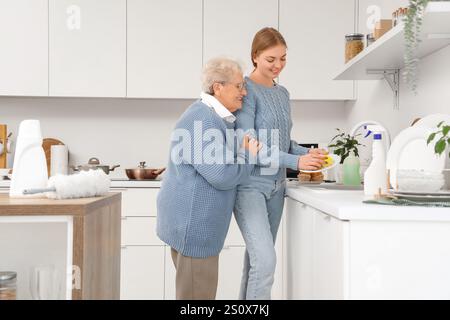 Glückliche Seniorin und ihre Enkelin waschen zusammen Geschirr in der Küche zu Hause Stockfoto