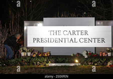 New York, Usa. Dezember 2024. Ein Mitarbeiter hinterlässt eine Gedenkstätte für Blumen am Haupteingang des Carter Presidential Center in Atlanta, GA, nach dem Tod des ehemaligen US-Präsidenten Jimmy Carter am Sonntag, den 29. Dezember 2024. Jimmy Carter, 39. Präsident der Vereinigten Staaten und Friedensnobelpreisträger 2002, starb friedlich am Sonntag in seinem Haus in Plains, Georgia. Mit 100 Jahren war er der am längsten gelebte Präsident in der Geschichte der USA. Foto von Mike Zarrilli/UPI Credit: UPI/Alamy Live News Stockfoto