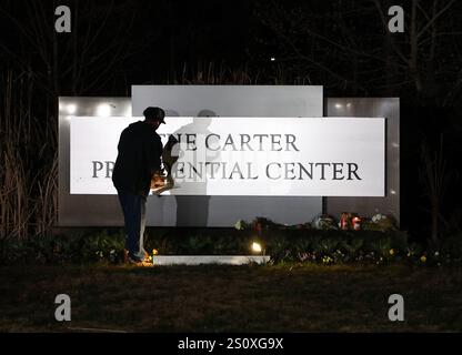 New York, Usa. Dezember 2024. Ein Passant hinterlässt Blumen als Gedenkstätte am Haupteingang des Carter Center in Atlanta, GA, nach dem Tod des ehemaligen Präsidenten der Vereinigten Staaten Jimmy Carter am Sonntag, den 29. Dezember 2024. Jimmy Carter, 39. Präsident der Vereinigten Staaten und Friedensnobelpreisträger 2002, starb friedlich am Sonntag in seinem Haus in Plains, Georgia. Mit 100 Jahren war er der am längsten gelebte Präsident in der Geschichte der USA. Foto von Mike Zarrilli/UPI Credit: UPI/Alamy Live News Stockfoto