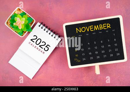 Kalender für November 2025 in schwarzer Tafel auf rotem Holzhintergrund. Stockfoto