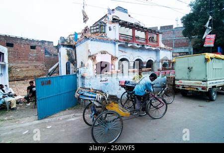 Eine Fahrrad-Rikscha, die vor einem alten zerbröckelnden Gebäude in Lucknow, Indien, geparkt hat. Stockfoto