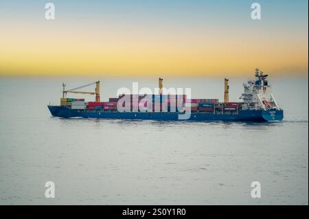 Dubai, VAE - 14. November 2024: Containerschiff in ruhiger See mit farbenfrohen Frachtcontainern. Seeverkehr und Logistik. Internationaler Handel. O Stockfoto