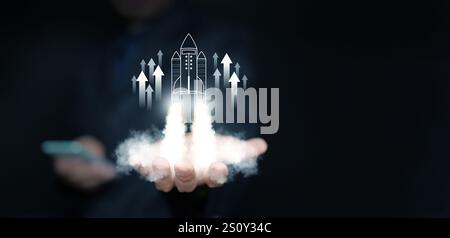 Startup Business-Konzept. Geschäftsmann startet ein virtuelles Raketensymbol mit Aufwärtspfeilen für schnelles Start-up. Beginn des Geschäftsbetriebs Ju Stockfoto