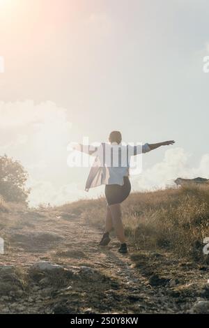 Woman Mountain Top Freedom: Eine Frau steht mit ausgestreckten Armen auf einem Berggipfel, genießt die Aussicht und fühlt sich frei. Stockfoto