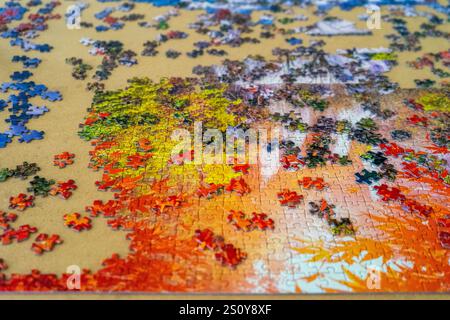 Draufsicht eines Puzzles, das gerade gebaut wird, mit seinen bunten Teilen, die im Hintergrund verstreut sind. Unterhaltungskonzept Stockfoto