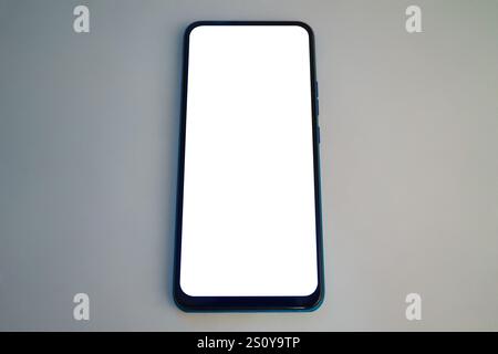 Ein Smartphone mit leerem Bildschirm liegt flach auf einer einfachen Oberfläche und unterstreicht das schlanke Design. Das Fehlen von Inhalten unterstreicht die Dimension des Telefons Stockfoto