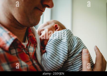 Vater hält Neugeborenes im Krankenhaus schlafend Stockfoto