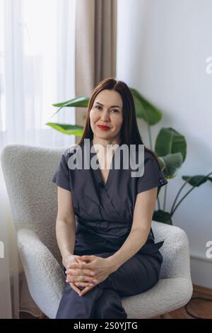 Lächelnder junger Kosmetologe, der im Stuhl sitzt, am Arbeitsplatz fröhlich aussieht, Hautpflegekonzept Stockfoto