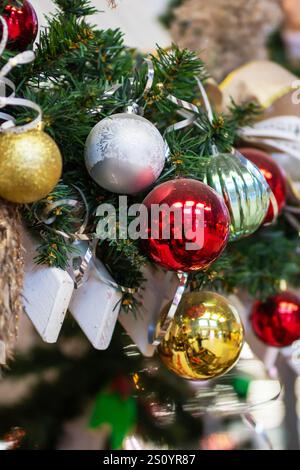 Eine detaillierte Nahaufnahme eines wunderschönen Weihnachtsbaums, der mit bunten Kugeln und eleganten Bändern für die Weihnachtszeit geschmückt ist Stockfoto