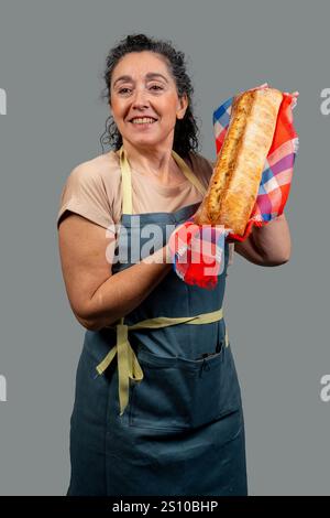 Lächelnde Bäckerin, die frisch gebackenes Brot in einem karierten Tuch hält Stockfoto