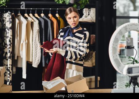 Die attraktive Stylistin der Millennials zeigt die Wahl der Mode, während sie in ihrem Studio Outfit-Tipps aufnimmt. Stockfoto