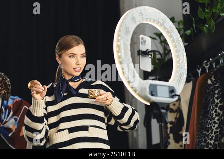 Selbstbewusste junge Frau zeigt trendige Kleidung und gibt über ihr Smartphone Einblicke in Mode. Stockfoto