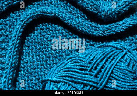 Türkisfarbenes texturiertes Jersey wird auf Stricknadeln aus halbwolltem Garn gestrickt. Das Konzept des Online-Kurses für handgemachte, Hobby- und Strickmode. Stockfoto
