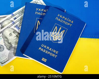 Ukrainische Pässe und Dollarwährung auf dem Hintergrund der ukrainischen Flagge. Finanzhilfe für das ukrainische Volk aus den Vereinigten Staaten Stockfoto