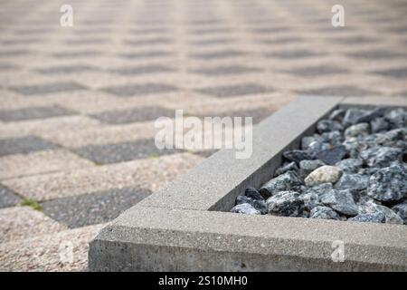 Ein Bürgersteig aus kleinen grauen Betonblöcken, die in einem Schachbrettmuster angeordnet sind. Der Bürgersteig wird auf dem Boden platziert und zwischen t sind kleine Lücken zu sehen Stockfoto