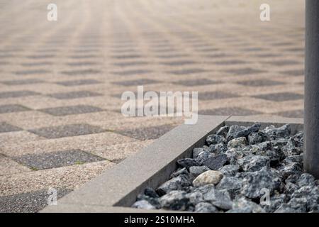 Ein Bürgersteig aus kleinen grauen Betonblöcken, die in einem Schachbrettmuster angeordnet sind. Der Bürgersteig wird auf dem Boden platziert und zwischen t sind kleine Lücken zu sehen Stockfoto