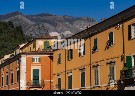 Die Apuanischen Alpen mit ihren Marmorbrüchen überblicken den Palazzo Diana auf der Piazza Alberica, Carrara, Italien. Stockfoto