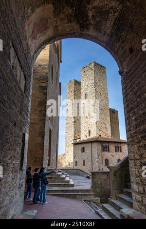 Die zwei Salvucci Towers auf der Piazza della Erbe in der mittelalterlichen Stadt San Gimignano, Italien. Die Fassade der Collegiata di Santa Maria Assunta C. Stockfoto