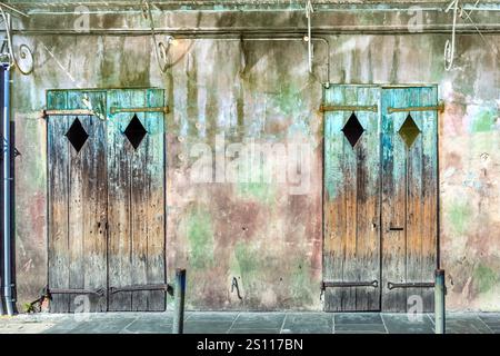 Alte verrottete Holztüren mit abblätternder Farbe im historischen Viertel des French Quarter in New Orleans, die ältere Zeiten symbolisieren Stockfoto