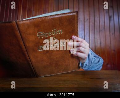 Ein Kind, das Ein Menü in Einem traditionellen deutschen Restaurant hält Stockfoto