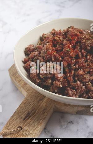 Rohes Hackfleisch, mariniert mit Gewürzen und Kräutern, in einer Schüssel, Hackfleisch mit Gewürzen, Blick von oben, hausgemacht, keine Leute Stockfoto