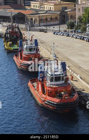 Hochwinkelblick auf angedockte orange, weiße und blaue Capo D'Orlando und Megrez Schlepper plus größere gelbe und grüne Schlepper, Hafen von Messina, Sizilien, Ita Stockfoto