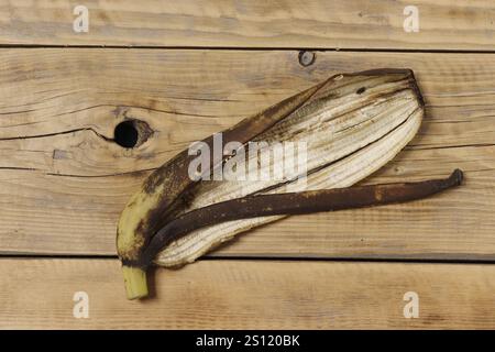 Schälen Sie mit braunen Flecken von einer alten Banane auf einem hölzernen Tisch mit Blick von der Tischplatte. Stockfoto