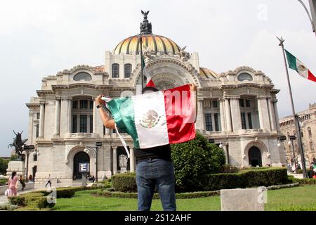 Mexiko-Stadt, Mexiko - 6. September 2023: Der Mann hält die mexikanische Flagge vor dem Palacio de Bellas Artes, um die nationalen Feiertage der Unabhängigkeit zu feiern Stockfoto