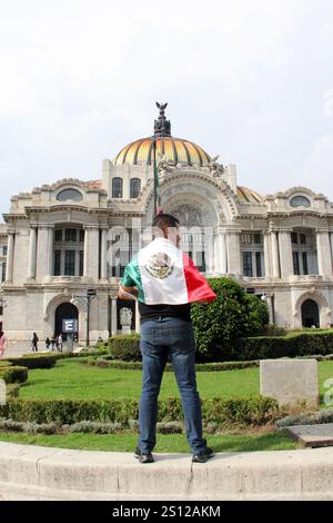 Mexiko-Stadt, Mexiko - 6. September 2023: Der Mann hält die mexikanische Flagge vor dem Palacio de Bellas Artes, um die nationalen Feiertage der Unabhängigkeit zu feiern Stockfoto