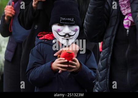 Quito, Ecuador. Dezember 2024 30. Ein Junge, der eine Maske trägt, nimmt an der Kundgebung Teil. Der Regen ist gekommen und 22 Tage sind vergangen, seit die vier Kinder aus Las Malvinas in Guayaquil verschwunden sind. Dutzende von Menschen gehen weiterhin auf die Straße, um friedlich zu demonstrieren und fordern den Staat auf, sie lebend zurückzubringen. Die Verwandten der Kinder Steven Medina, Saul Arboleda und die Brüder Ismael und Josue Arroyo, die am 8. Dezember im Süden von Guayaquil verschwanden, warten immer noch auf die Bestätigung der Identität der vier verbrannten Leichen, die in einem Fluss nahe dem Luftwaffenstützpunkt Taura gefunden wurden. Cred Stockfoto