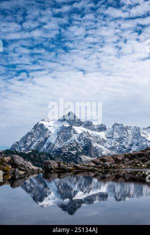 Unter hellerem Himmel spiegelt sich der Mount Shuksan mit frischem Schnee in einem kleinen See am Huntoon Point in der Nähe des Mount Baker. Stockfoto