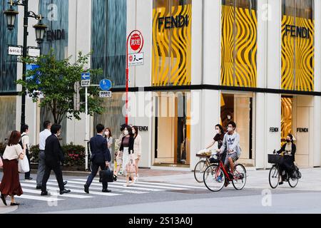 TOKIO, JAPAN - 26. Mai 2021: Radfahrer und Fußgänger nutzen einen Fußgängerübergang bei einem Fendi-Geschäft im Einkaufszentrum Ginza Six. Stockfoto