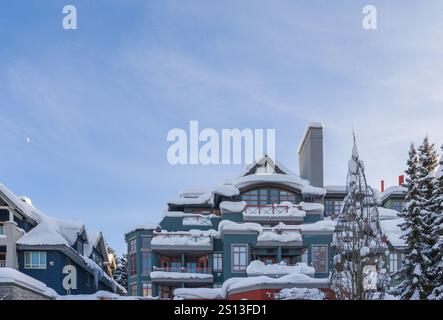 Wintertourismus in den Bergen - ein Spaziergang im alpinen Dorf mit Häusern, Hütten, Café und Skigebieten. Reinweißer Schnee und Sonnenlicht. Whistler, Stockfoto