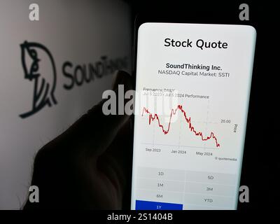 In dieser Abbildung hält eine Person ein Mobiltelefon mit der Website des US-amerikanischen Sicherheitstechnologie-Unternehmens SoundThinking Inc. Vor dem Logo. Stockfoto