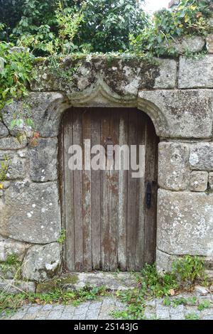 Alte Steinmauer mit Holztür, Frankreich, Bretagne, Finistere, Locronan Stockfoto