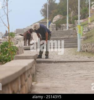 Mar del Plata. Buenos Aires. Argentinien. Ein älterer Mann spricht mit seinem Hund, der am Sommertag im Park spaziert Stockfoto