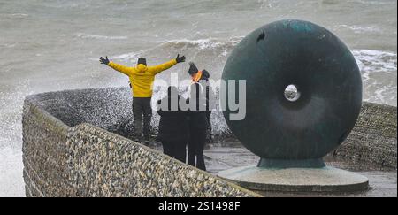 Brighton UK 31. Dezember 2024 - Wanderer werden nass, wenn Wellen an einem windigen Tag auf Brightons Küste krachen, da stürmisches Wetter viele Silvesterfeuerwerke im ganzen Land abgesagt hat: Credit Simon Dack / Alamy Live News Stockfoto