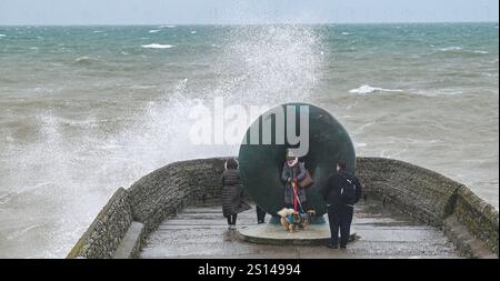 Brighton UK 31. Dezember 2024 - Wanderer werden nass, wenn Wellen an einem windigen Tag auf Brightons Küste krachen, da stürmisches Wetter viele Silvesterfeuerwerke im ganzen Land abgesagt hat: Credit Simon Dack / Alamy Live News Stockfoto