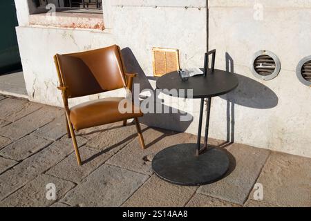 Venedig, Italien. Dezember 2024. Ein Stuhl und ein Tisch mit Kaffee und einer Zigarette drauf. Stockfoto