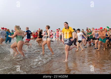 Hunderte von Menschen, viele davon in festlicher Kleidung, rasen am Exmouth Beach während des jährlichen Weihnachtstages Schwimmen, Devon, Großbritannien, 25. Dezember 2024. Stockfoto