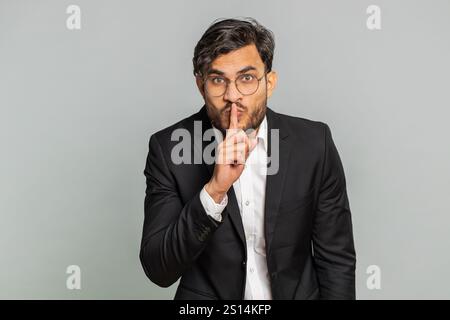 Bitte sei ruhig. Indischer Geschäftsmann drückt Zeigefinger auf die Lippen macht Stille Geste Zeichen sagt nicht geheim, hört auf, Klatsch zu reden, vertrauliche Privatsphäre. Arabian man Typ isoliert auf grauem Hintergrund Stockfoto